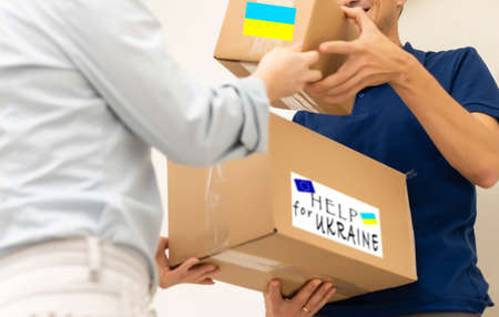 Volunteer cyrrying box with Humanitarian aid for Ukrainian refugees in streetの写真素材