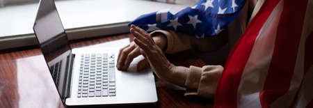 very old senior woman with laptop and usa flagの写真素材