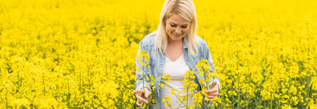 Portrait of attractive woman on blooming rapeseed field with sunset light. Yellow flowers and happy...
