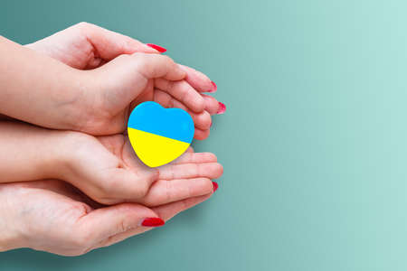 The national flag of ukraine with the coat of arms in female hands. Flat lay, copy spaceの写真素材