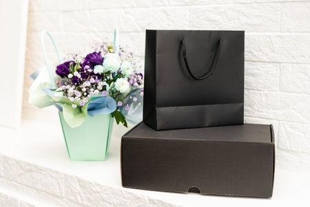 bouquet and black gift bag on white background.