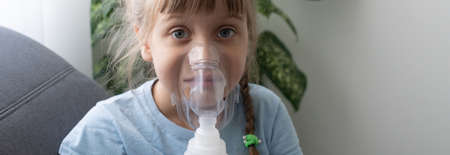sick little girl makes inhalation over grey background with copy space. Girl making inhalation with nebulizer at home. child asthma inhaler inhalation nebulizer steam sick coughの写真素材