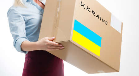 A man holds a box of aid for Ukrainian refugees and poor citizens who find themselves in a war between Ukraine and Russia. Humanitarian aid concept. Donate for refugees.の写真素材