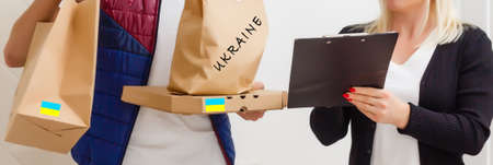 A man holds a box of aid for Ukrainian refugees and poor citizens who find themselves in a war between Ukraine and Russia. Humanitarian aid concept. Donate for refugees.の写真素材
