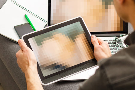 closeup of a young caucasian man watching a nude woman in his tablet computer