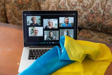 online behind a laptop from home against the background of the flag of Ukraine, martial law in the country, online broadcast of local news, stop war and patriotの写真素材