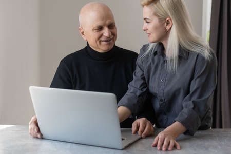 Happy smiling young girl teaching and showing new computer technology to her grandfather.の写真素材