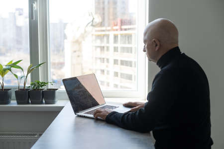 Portrait of senior man at home working on laptopの写真素材