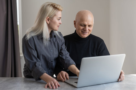 Attractive young woman helping senior man with questionnaire, pensioneer filling papers at nursing home, having assistanceの写真素材