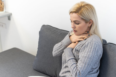 Attractive woman s sitting on bed with sore throat