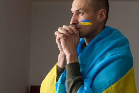 Young sad man with Ukrainian flag symbol on her face crying, stop the war concept, pray for Ukraineの写真素材