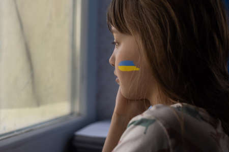Little girl with Ukrainian flag ribbon praying. Symbol of peace and pray for Ukraine.の写真素材