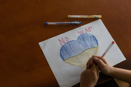 childrens drawing, flags of ukraine are drawn on a sheet, childrens hands hold a heart made, war...