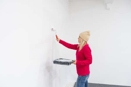 Female decorator painting wall with roller indoorsの写真素材