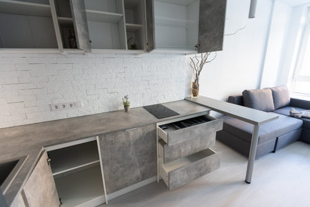 Interior of the small living equipped kitchen in studio apartments in minimalistic style with light...