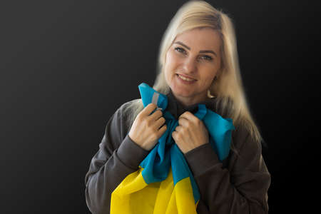 Beautiful young woman with flag of Ukraine on dark background.の写真素材