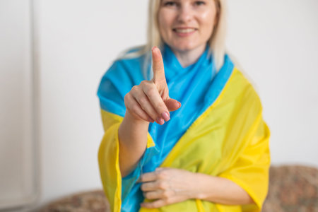 blonde woman wrapped in Ukraine flag. Support for Ukraine conceptの写真素材