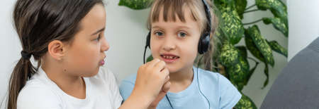 Two girls working on laptop, smiling and older sister help youngerの写真素材