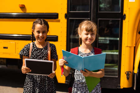 Lucky to meet each other. Cheerful smart schoolgirls. Happy schoolgirls outdoors. Small schoolgirls wear school uniform. Cute schoolgirls looking charming. Ending of school year.の写真素材