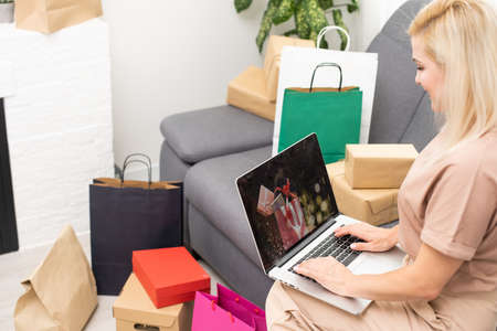 Young woman with laptop and shopping bags at home. Black Friday saleの写真素材