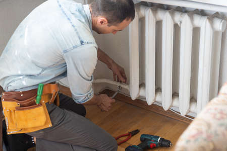 Repair heating radiator close-up. man repairing radiator with wrench. Removing air from the radiator.の写真素材