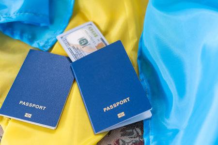 Biometric foreign passport with money lies on the national flag of Ukraine yellow-blue.