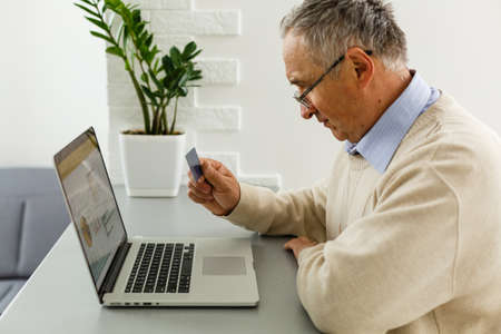 Smiling elderly senior man with laptop at homeの写真素材