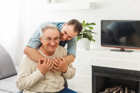 Senior Father With Adult Son Relaxing On Sofa At Home