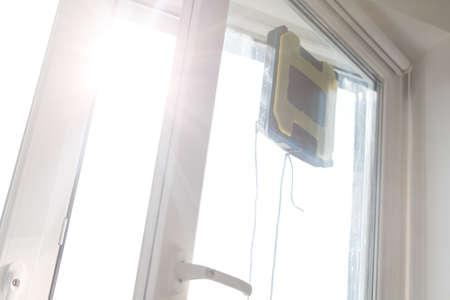 Robot window cleaner work on dirty window. Cleaning the house with smart devices. Automatic vacuum robots for cleaning windows, an assistant for the home.の写真素材