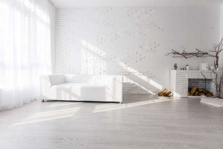 Bright and clean interior design of a luxury living room with hardwood floors, fireplace and sofaの写真素材