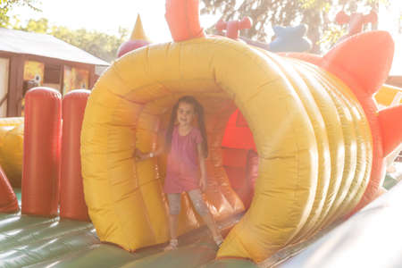 Happy little girl having lots of fun on a jumping castle during slidingの写真素材