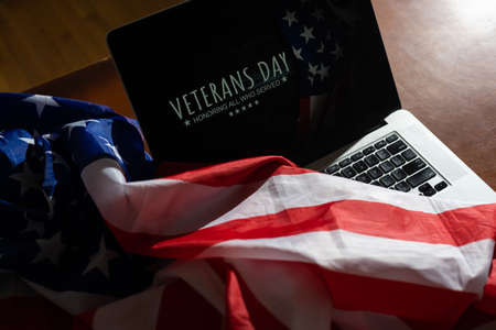 veterans day written in laptop with flag of the United States, on a rustic wooden backgroundの写真素材