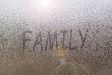 Foggy glass on window with written finger word family overcast wet windowの写真素材