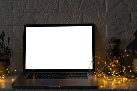 Front view of the laptop with mockup screen on the desk. Christmas gifts and decorations behind laptop. Holiday online shopping or sale. Internet goods. Copy space. Reindeer, Christmas tree.の写真素材