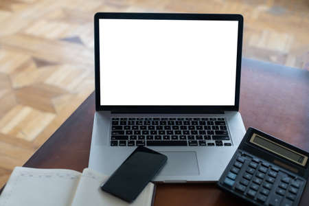 modern laptop computer with blank screen and copy space at workplace in office. Bills document, calculator and stationery on wooden tableの写真素材