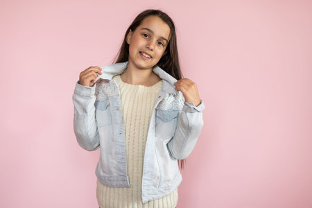 Portrait of pretty kid standing looking wearing trousers isolated over pink background