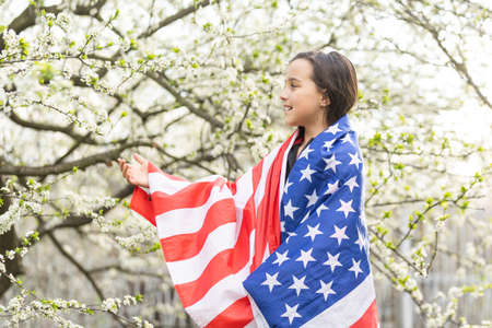 Happy adorable little girl smiling and waving American flag. Patriotic holiday. Happy kid, cute little child girl with American flag. USA celebrate 4th of July. Independence Day concept.の写真素材