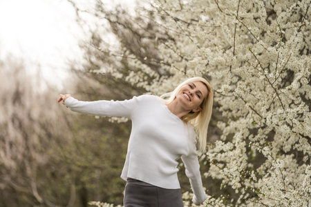 Portrait of a young woman in a blooming orchard. Blonde woman