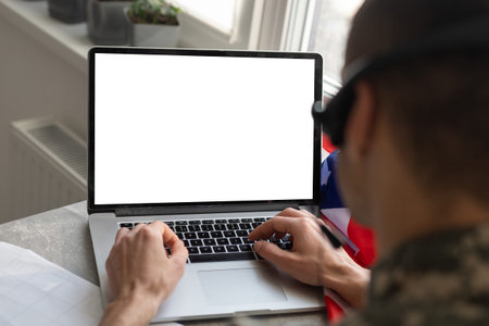 military man gesturing in office near laptop with blank screen, usa flag.