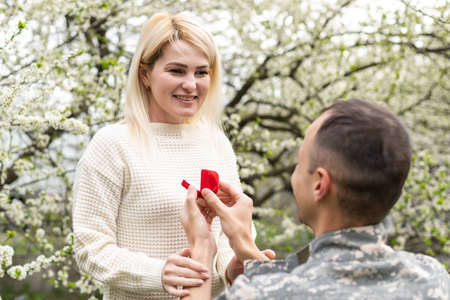 Young military couple in park showing engagement ring.の写真素材
