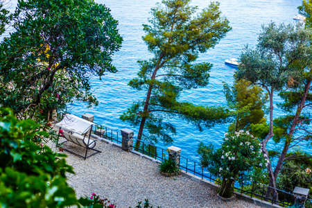Fishing boats moored on water in harbor of Ligurian and Mediterranean Sea near coastline of Riviera di Levante of National park Cinque Terre Coast with blue sky, Riomaggiore village, Liguria, Italy.の写真素材