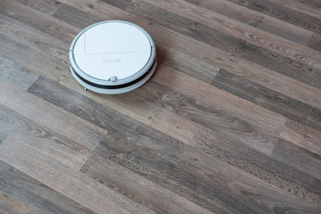 Hoovering floor with modern robotic vacuum cleaner indoors, closeupの写真素材