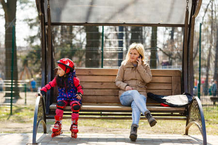 mother and daughter resting on bench on streetの写真素材