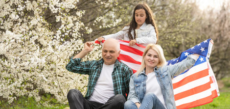 Portrait of happy family celebrating 4th July Independence Day holding silhouette usa national flag...