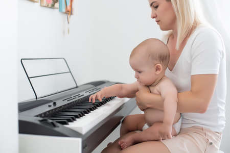 Little girl and her mother playing the pianoの写真素材