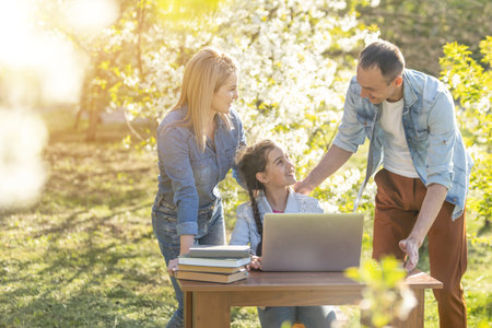 Happy family of four parents and cute little girl studying on laptop, enjoy using laptop watching...