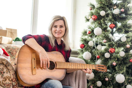 Young woman playing guitar on Christmas holidays. Hygge concept. musician, hobby, lifestyleの写真素材