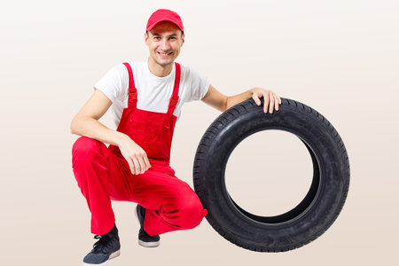 Mechanic carrying a tyre on a white backgroundの写真素材