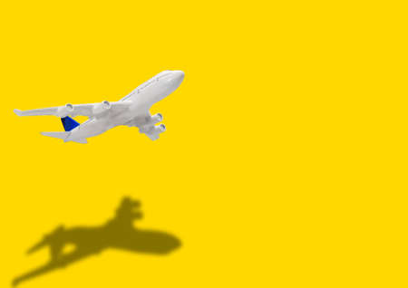 Miniature toy airplane on yellow background. Trip by airplane.の写真素材