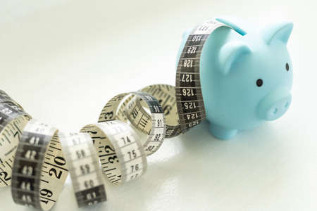 Piggy bank with tape measure on white backgroundの写真素材